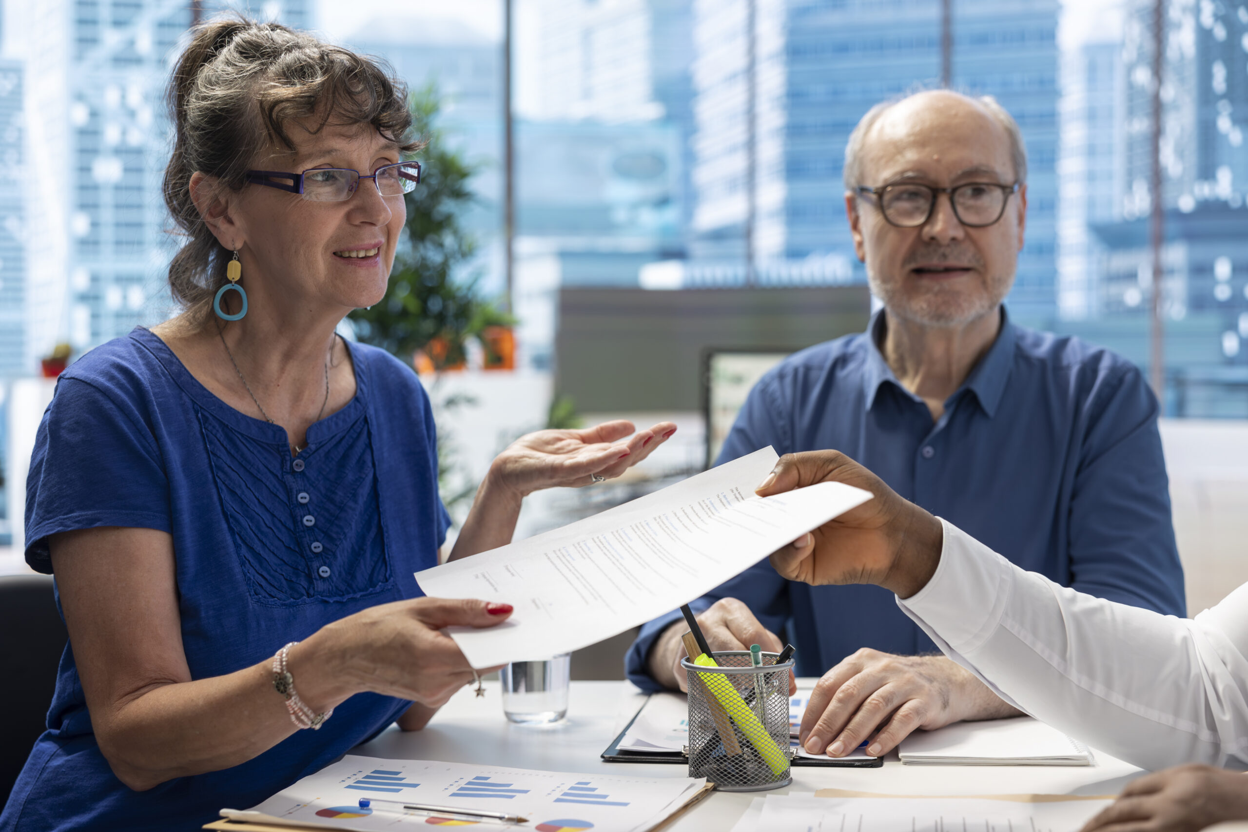 Financial advisor giving the retirement plan documents to old people, securing a contract with life insurance policy. Broker counseling clients to choose a suitable pension option.